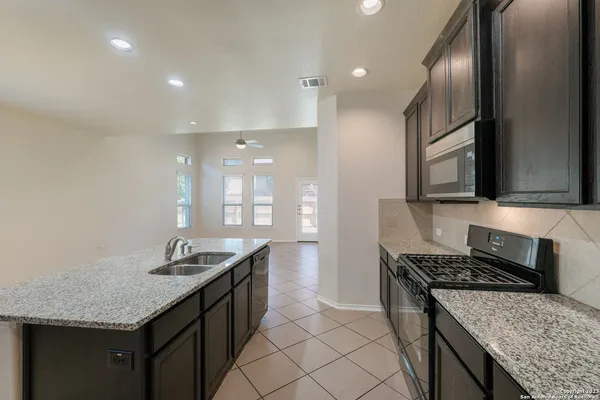 a kitchen with granite countertop stainless steel appliances a sink stove and cabinets