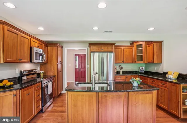 a kitchen with stainless steel appliances granite countertop a stove a sink and a microwave