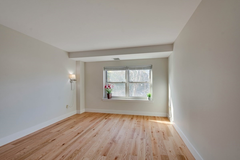 1 Watermill Place, Unit 308 Arlington, MA 02476 - Photo 8 of 27 an empty room with wooden floor and windows