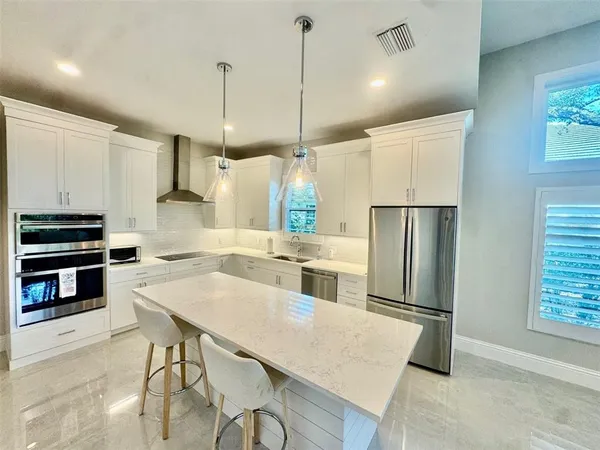 a kitchen with stainless steel appliances a stove a sink island and a refrigerator with wooden floor