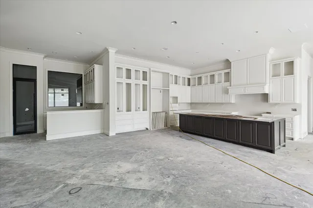 a large white kitchen with kitchen island granite countertop a sink and cabinets