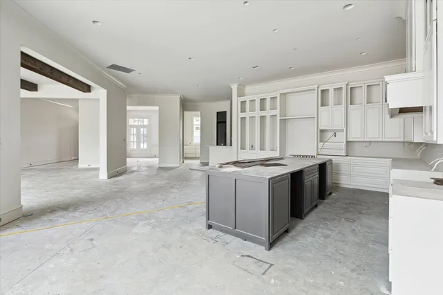 a large white kitchen with granite countertop a sink and white cabinets