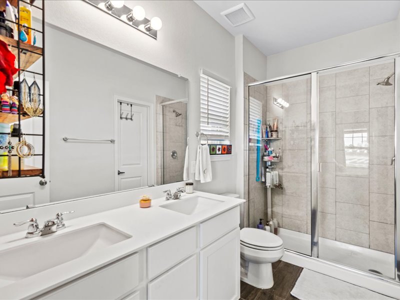 8201 Daisy Cutter Crossing Georgetown, TX 78626 - Photo 13 of 31 Full bathroom with double vanity, a shower stall, and dark wood finished floors