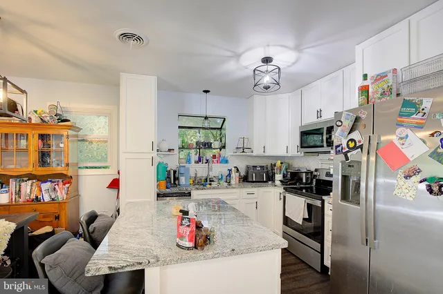 a kitchen with stainless steel appliances granite countertop a sink dishwasher stove and microwave with wooden floor