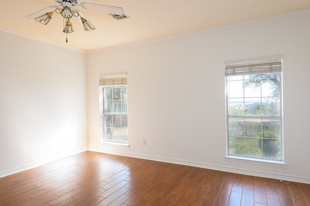 4488 Blue Ridge Drive Belton, TX 76513 - Photo 18 of 35 an empty room with wooden floor chandelier fan and windows