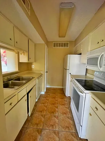 a kitchen with a sink a stove top oven and cabinets