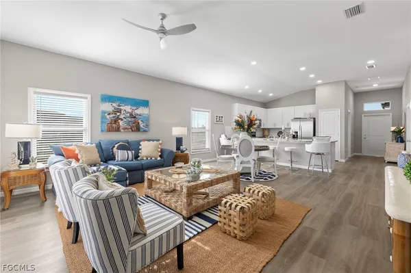 a living room with furniture kitchen view and a wooden floor