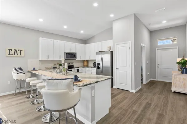 a kitchen with stainless steel appliances granite countertop a refrigerator a sink a stove a dining table and chairs
