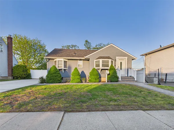 a front view of a house with a big yard and potted plants