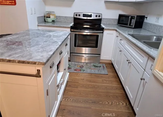 a kitchen with granite countertop a sink stove and cabinets