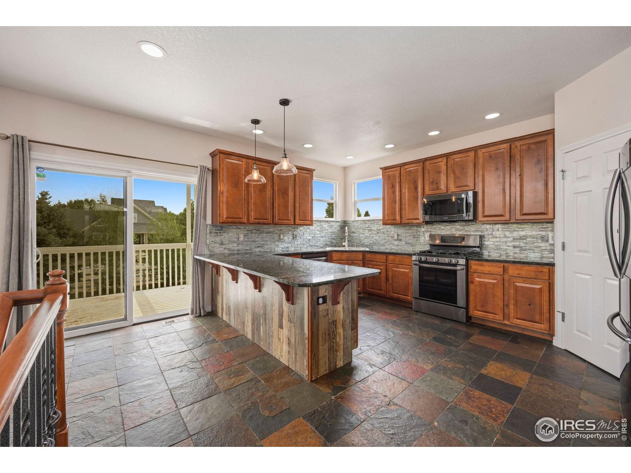 3427 Red Hawk Lane Longmont, CO 80504 - Photo 6 of 33 a kitchen with stainless steel appliances granite countertop a stove top oven a sink dishwasher a dining table and chairs with wooden floor