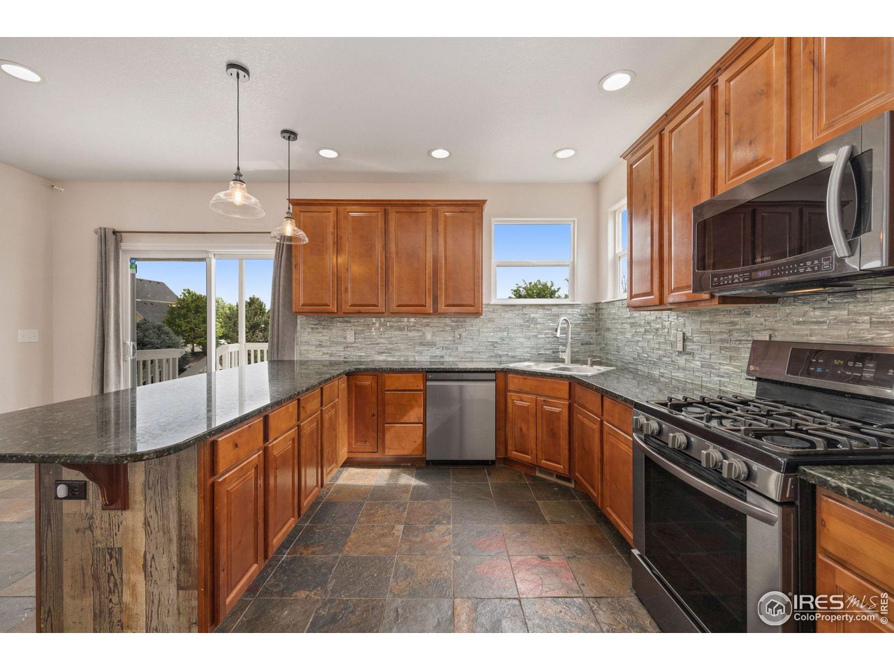 3427 Red Hawk Lane Longmont, CO 80504 - Photo 7 of 33 a kitchen with stainless steel appliances kitchen island granite countertop a stove a sink and a microwave