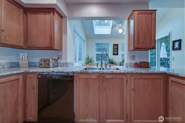a kitchen with granite countertop a sink dishwasher stove and cabinets