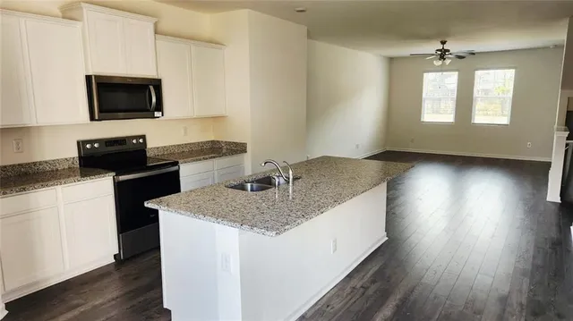 a kitchen with granite countertop a sink and a stove top oven