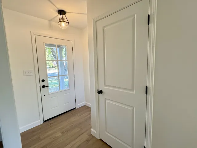 an empty room with wooden floor closet and windows