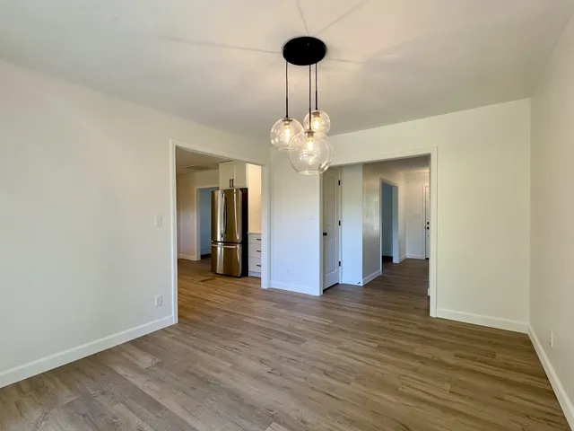 a view of an empty room with wooden floor and chandelier