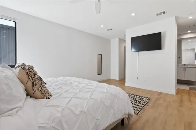 a bedroom with a bed tv and wooden floor