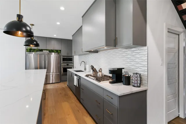 a kitchen with stainless steel appliances granite countertop a sink a stove and a refrigerator
