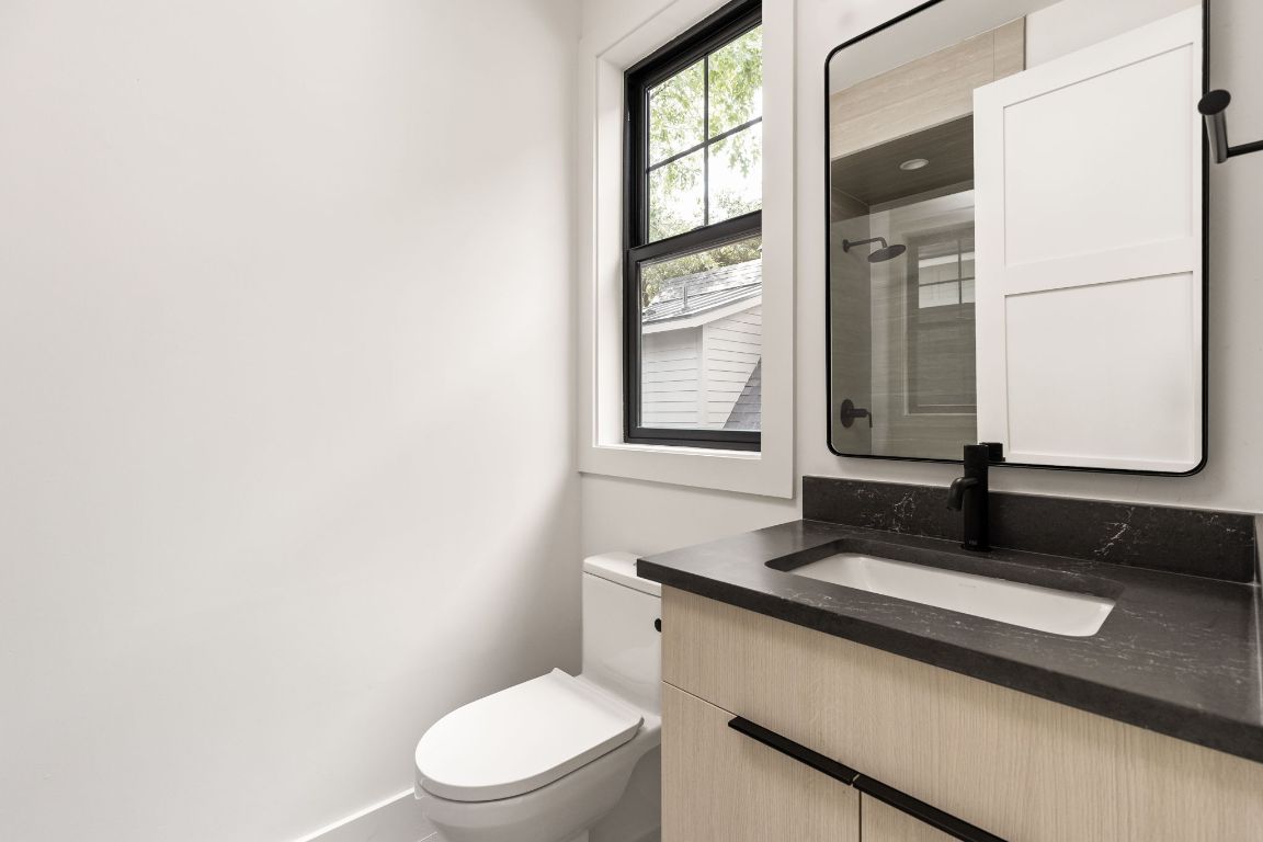 2707 Stacy Lane, Unit 1 Austin, TX 78704 - Photo 26 of 40 a bathroom with a granite countertop sink toilet and mirror