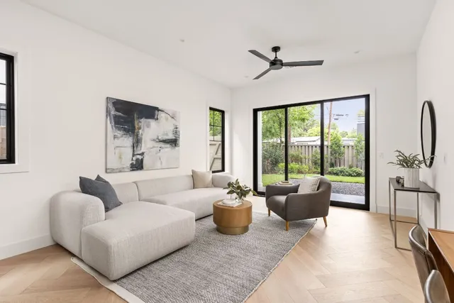 a living room with stainless steel appliances kitchen island granite countertop a refrigerator a stove a sink a oven and a dining table with wooden floor