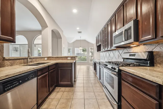 a large kitchen with stainless steel appliances granite countertop a stove and a sink