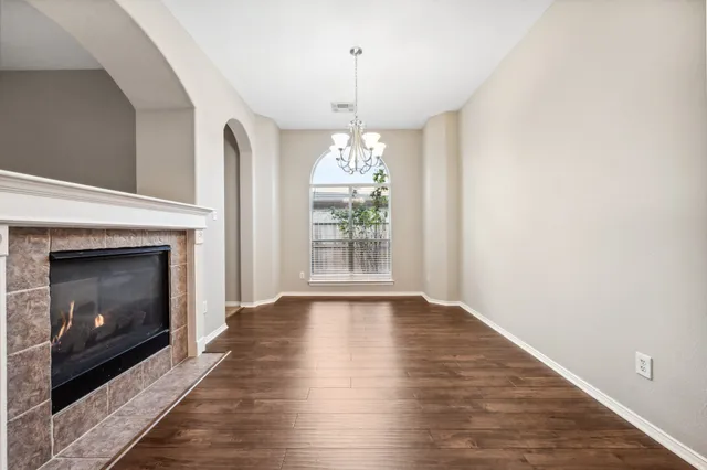 a view of an empty room with wooden floor fireplace and a window
