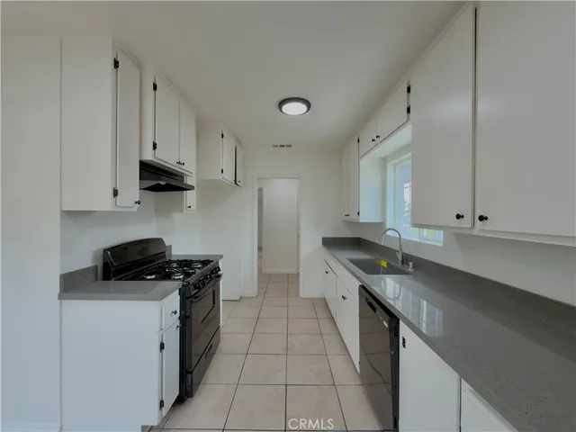 a kitchen with granite countertop a sink a stove and cabinets