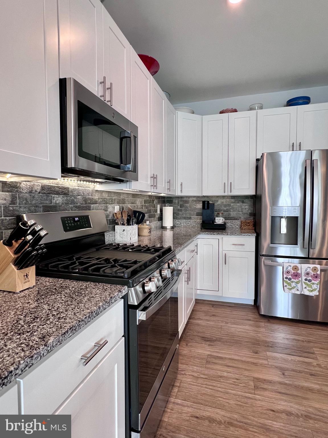 1143 Kayla Lane Townsend, DE 19734 - Photo 46 of 86 a kitchen with stainless steel appliances granite countertop a stove top oven a refrigerator a sink and dishwasher with wooden floor