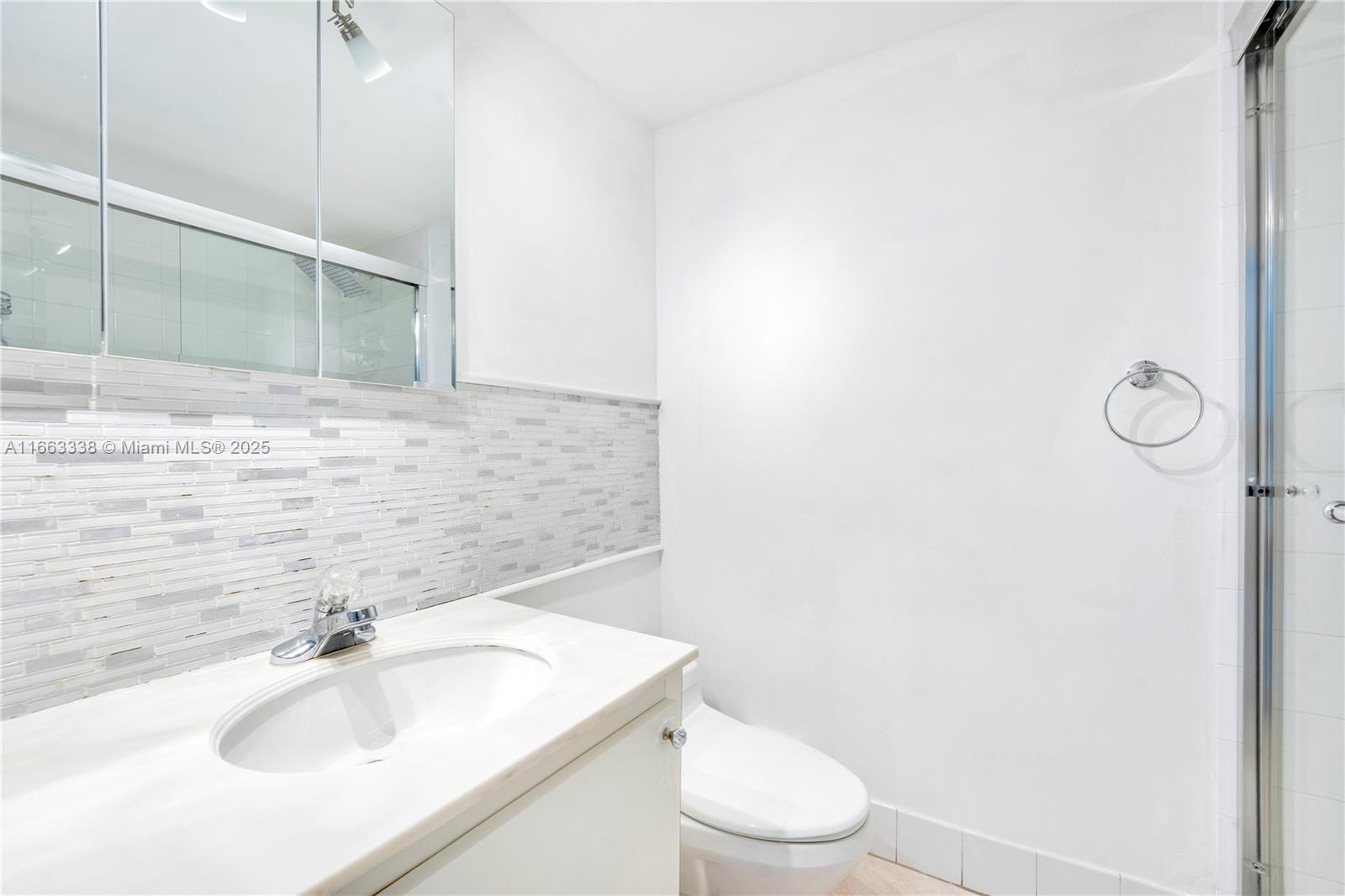 5151 Collins Avenue, Unit 925 Miami Beach, FL 33140 - Photo 16 of 23 a bathroom with a sink a toilet a mirror and shower