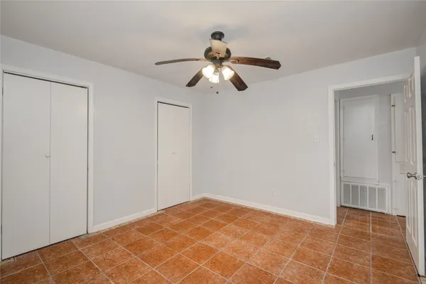 a view of an empty room and chandelier fan