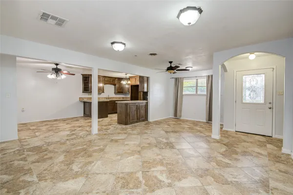 an empty room with kitchen view and windows