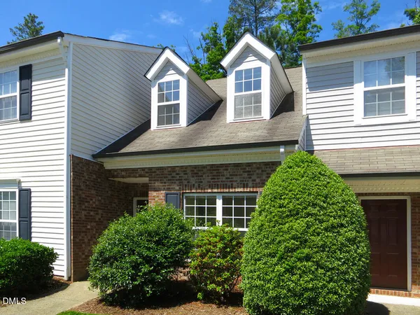 a front view of a house with a yard and potted plants