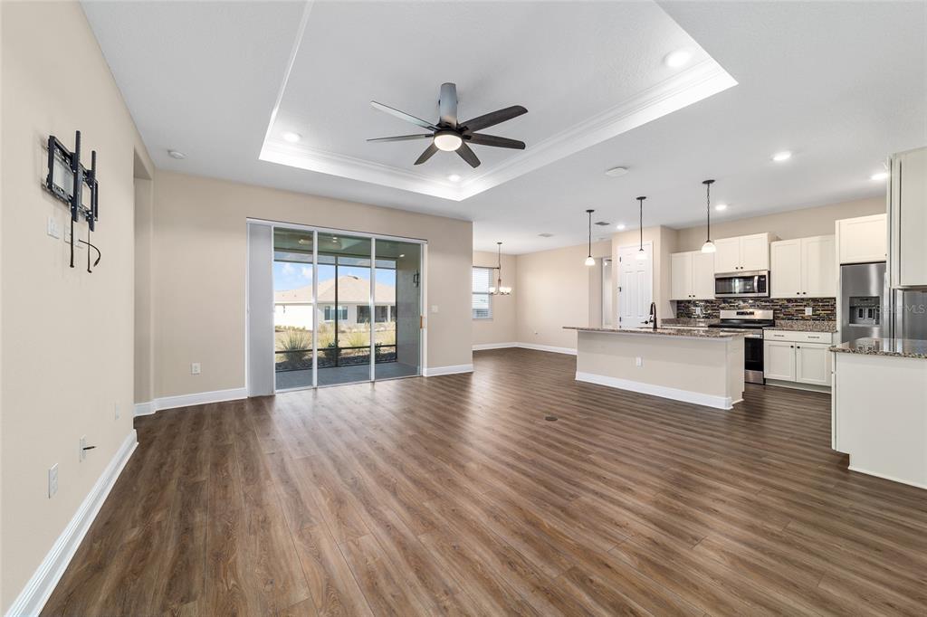 9778 Southwest 103rd Avenue Ocala, FL 34481 - Photo 12 of 57 a view of an empty room with wooden floor and a kitchen