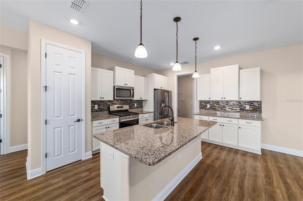 9778 Southwest 103rd Avenue Ocala, FL 34481 - Photo 23 of 57 a kitchen with stainless steel appliances kitchen island granite countertop a stove refrigerator and cabinets