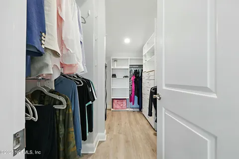 a view of walk in closet with clothes and shoes