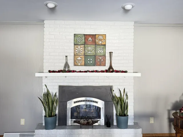 a living room with a fireplace and potted plants