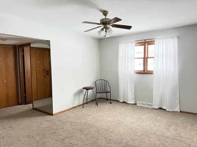 an empty room with windows and fan