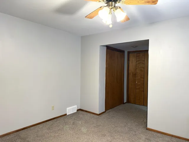 an empty room with a chandelier fan and closet