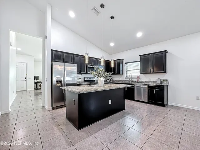 a large kitchen with a large counter top stainless steel appliances and cabinets