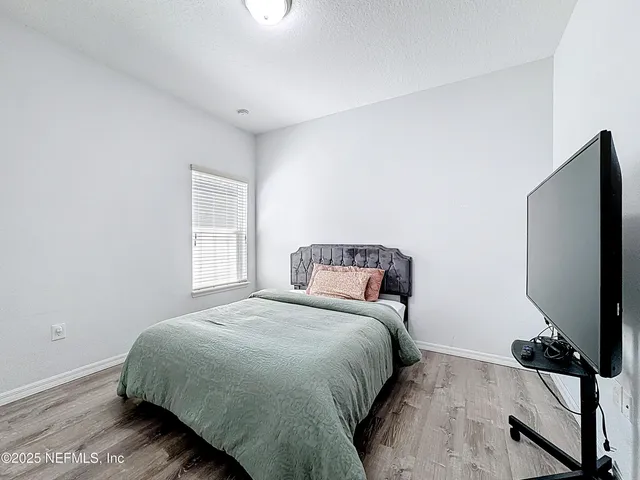 a bedroom with a bed tv and a window