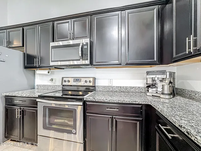 a kitchen with granite countertop a sink stove and microwave