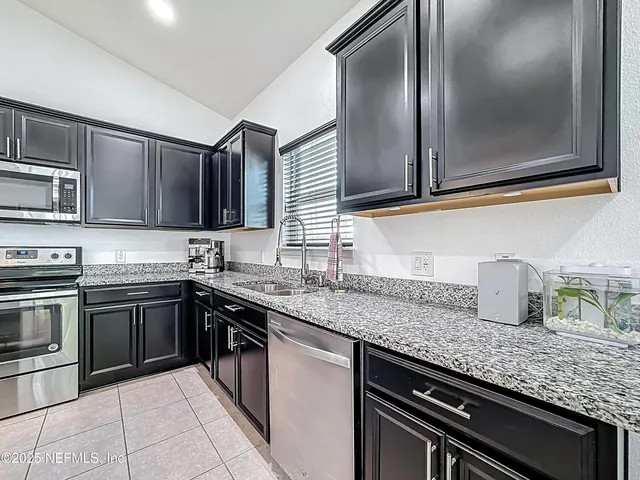 a kitchen with stainless steel appliances granite countertop a sink stove and microwave