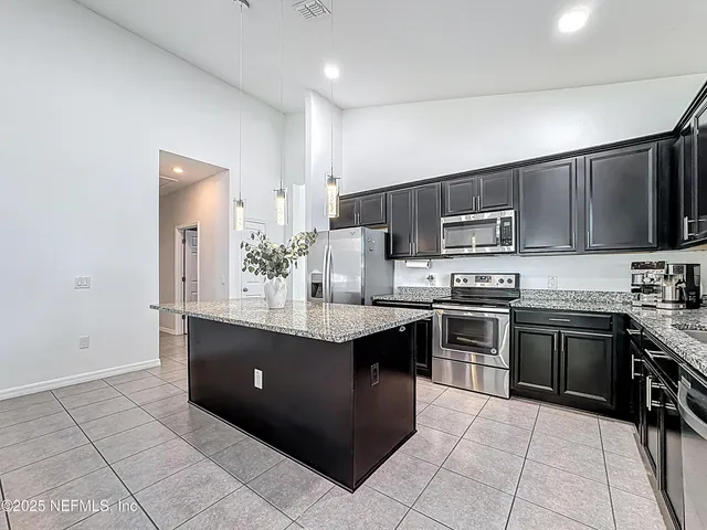 a kitchen with stainless steel appliances granite countertop a stove top oven a sink dishwasher and a refrigerator