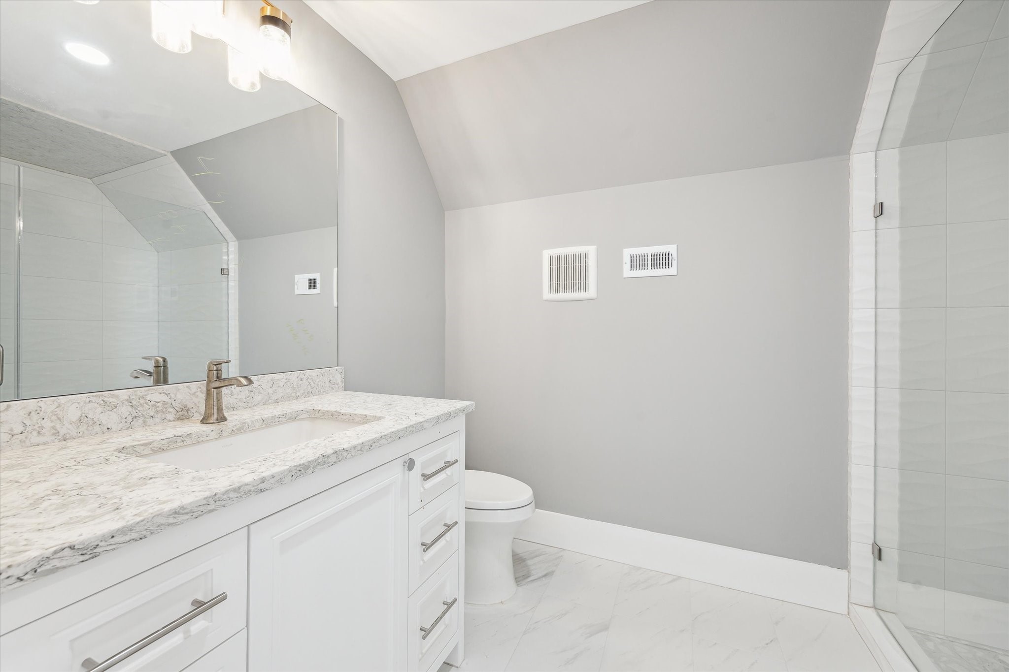2216 Tangley Street Houston, TX 77005 - Photo 21 of 44 This bathroom features a modern design with a sleek white vanity, marble countertop, large mirror, and a spacious glass-enclosed shower. The neutral gray walls and bright lighting create a fresh and inviting atmosphere.