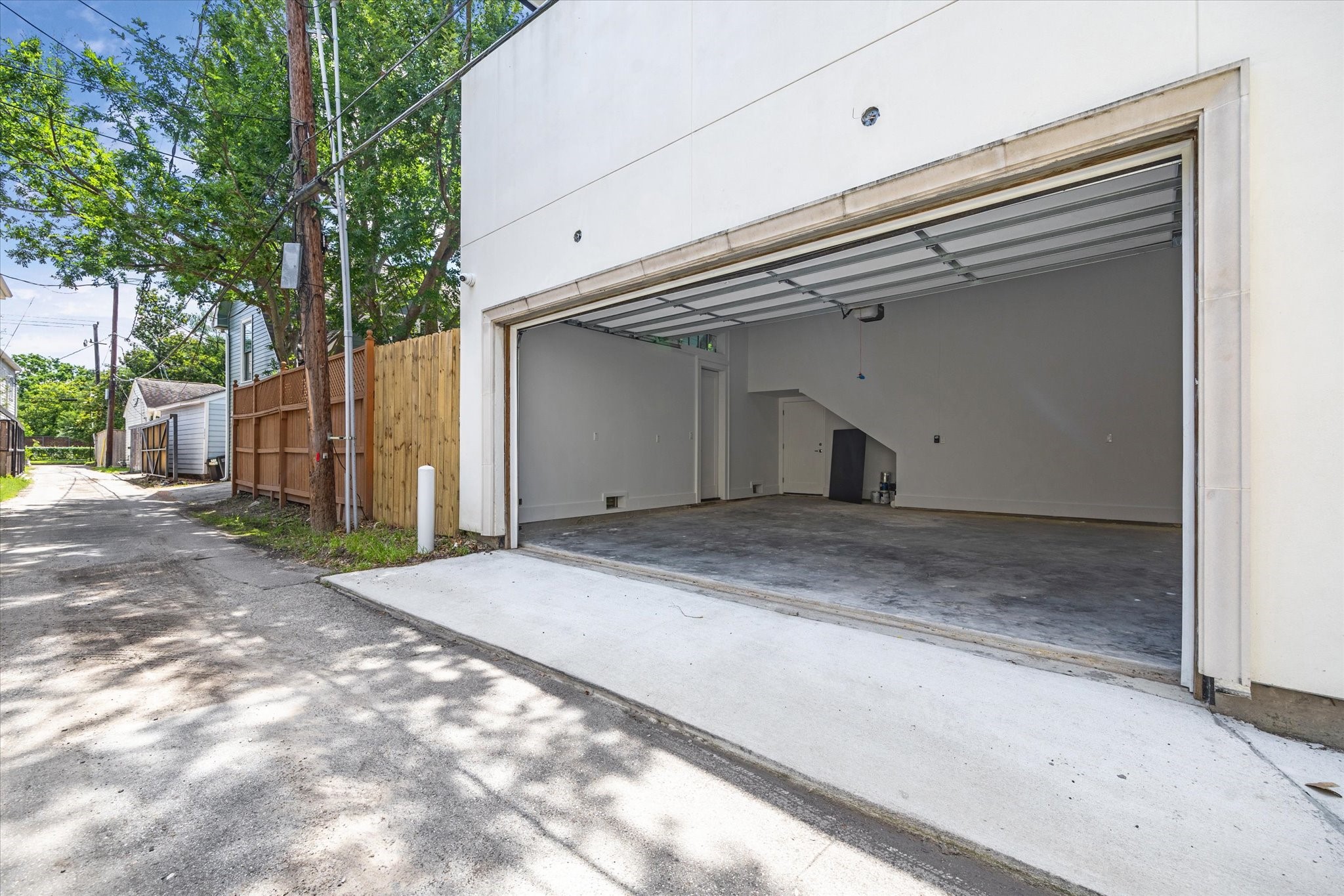 2216 Tangley Street Houston, TX 77005 - Photo 26 of 44 The spacious two-car garage with a clean concrete floor has an automatic garage door opener and access from a back alley. The garage is attached and opens into the back hall/mudroom of the house and also to the covered outdoor patio. There is a wooden fence, offering privacy.
