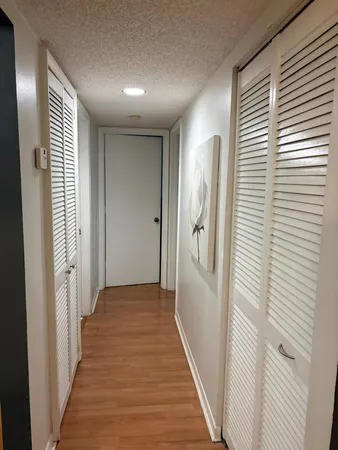 a view of a hallway with wooden floor and closet area