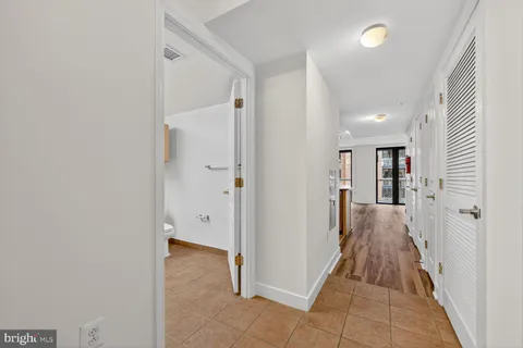 a view of a hallway with wooden floor and a bathroom