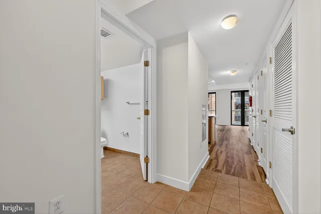 a view of a hallway with wooden floor and a bathroom