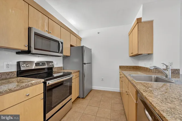 a kitchen with granite countertop a sink stove and refrigerator