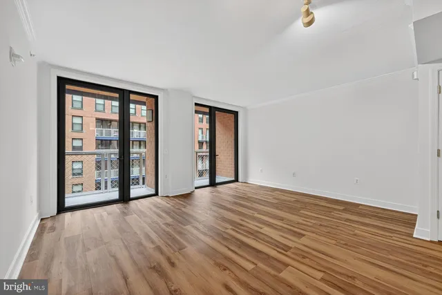 a view of an empty room with wooden floor and a window